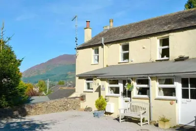 a house with a bench in front of it at Cottage - Sleeps 4 - Pets Ok - Garden - Parking in Keswick