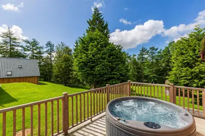 a hot tub on a deck with a fence at Lord Galloway 37 with Hot Tub in Newton Stewart