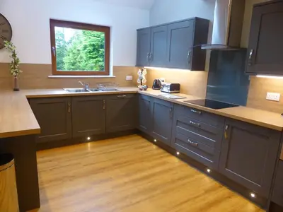 a kitchen with dark blue cabinets and a window at Lord Galloway 37 with Hot Tub in Newton Stewart