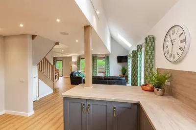 a kitchen and living room with a large clock on the wall at Lord Galloway 39 with Hot Tub in Newton Stewart
