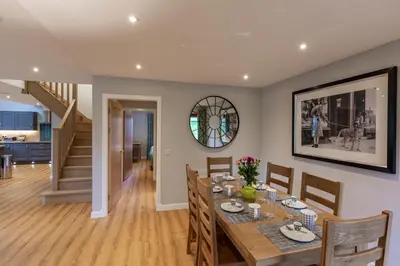 a dining room with a table and chairs and a staircase at Lord Galloway 39 with Hot Tub in Newton Stewart