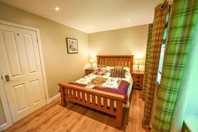 a bedroom with a bed with a wooden headboard at Bluebell Lodge 2 with Hot Tub in Newton Stewart