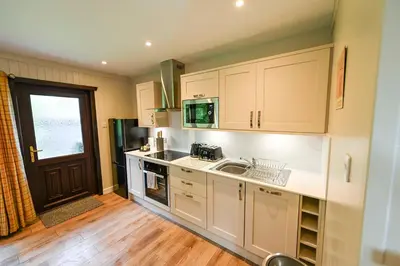 a kitchen with white cabinets and a sink at Bluebell Lodge 3 with Hot Tub in Newton Stewart