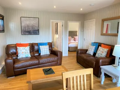 a living room with leather couches and a table at Birch Lodge 17 with Hot Tub in Newton Stewart