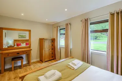 a bedroom with a bed and a desk and a window at Bluebell Lodge 4 with Hot Tub in Newton Stewart