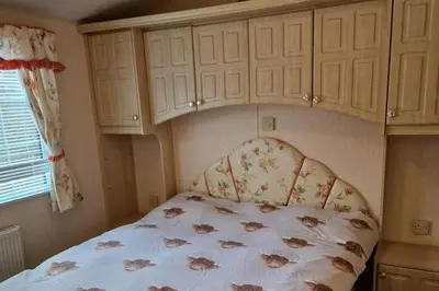 a bedroom with a bed with a floral bedspread at Caravan - Sleeps 4 - Pet friendly - Parking in Newton Stewart