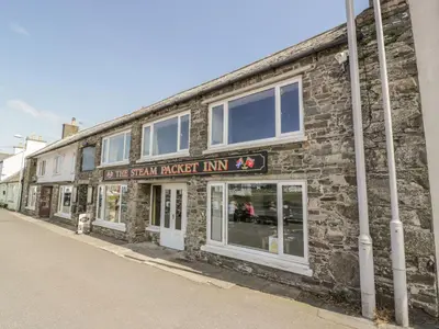 a brick building with a sign that reads the sixth rocket inn at Tides Reach in Newton Stewart