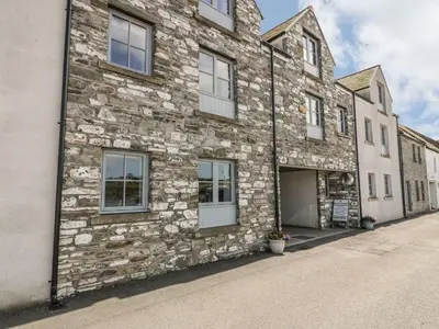 an old stone building with a garage on a street at Tides Reach in Newton Stewart