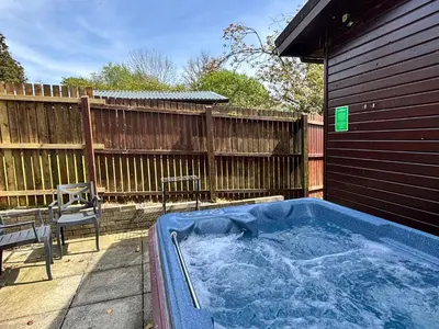 a hot tub in a yard next to a fence at Bluebell Lodge 7 with Hot Tub in Newton Stewart