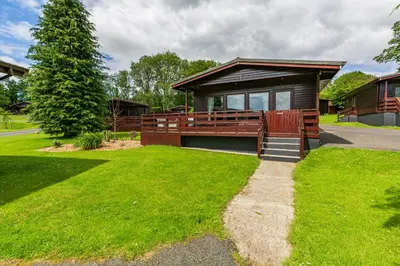 a house with a porch and a grass yard at Bluebell Lodge 10 with Hot Tub in Newton Stewart