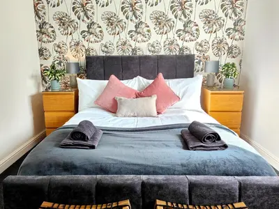 a bedroom with a large bed with pink pillows at Sanderson House in Cleator Moor