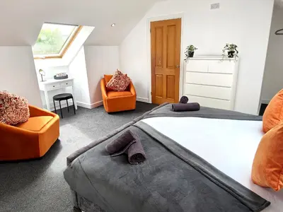 a bedroom with a large bed and two orange chairs at Sanderson House in Cleator Moor