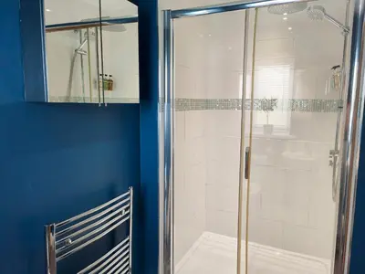 a bathroom with a shower with a blue wall at Sanderson House in Cleator Moor