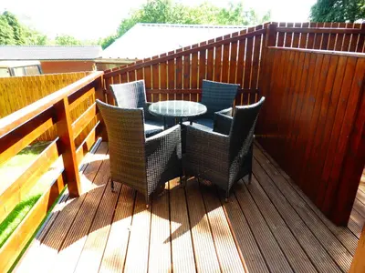 a patio with a table and chairs on a deck at Birch Lodge 13 with Hot Tub in Newton Stewart