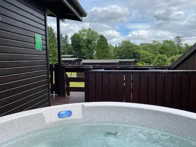 a jacuzzi tub in a backyard with a fence at Birch Lodge 14 with Hot Tub in Newton Stewart