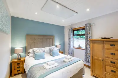 a bedroom with a large bed with blue walls at Birch Lodge 14 with Hot Tub in Newton Stewart
