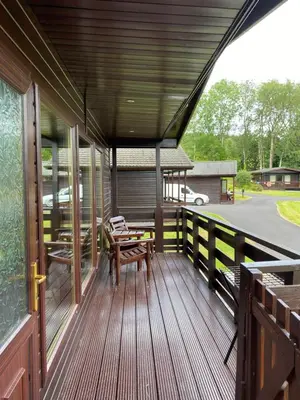 a wooden porch with a table and benches on it at Birch Lodge 14 with Hot Tub in Newton Stewart