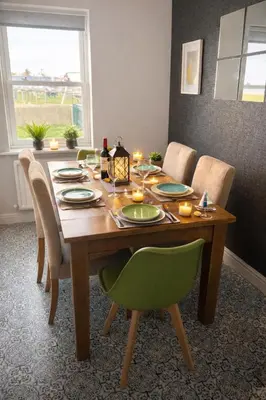 a dining room table with chairs and a table with candles at Sunset House On The Beach in Maryport