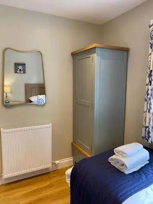 a bedroom with a blue bed and a mirror at Birch Lodge 18 with Hot Tub in Newton Stewart