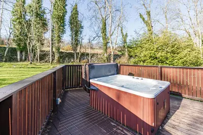 a hot tub on a deck with a fence at Birch Lodge 19 with Hot Tub in Newton Stewart