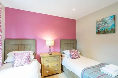 two beds in a room with a purple wall at Birch Lodge 20 with Hot Tub in Newton Stewart