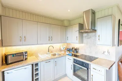 a kitchen with white cabinets and a sink and a microwave at Birch Lodge 20 with Hot Tub in Newton Stewart