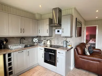 a kitchen with white cabinets and a couch in it at Birch Lodge 20 with Hot Tub in Newton Stewart