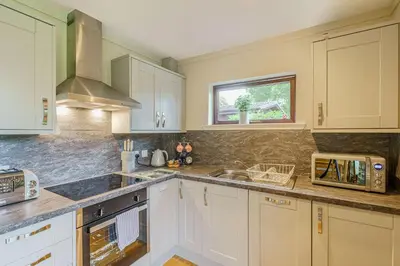 a kitchen with white cabinets and a sink and a window at Birch Lodge 21 with Hot Tub in Newton Stewart