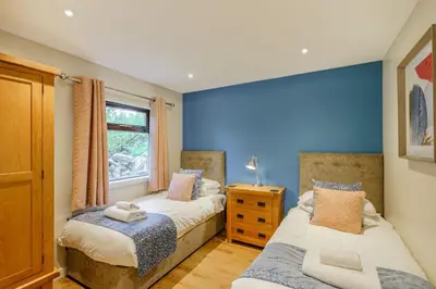 two beds in a bedroom with a blue wall at Birch Lodge 23 with Hot Tub in Newton Stewart