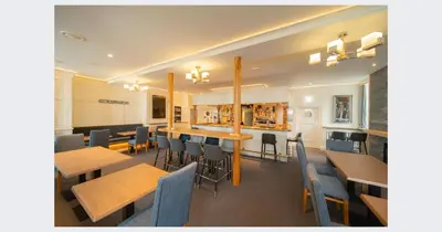 a restaurant with wooden tables and chairs and a bar at Shore Hotel Laxey in Laxey