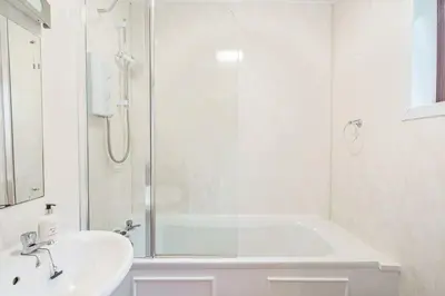 a white bathroom with a shower and a sink at Birch Lodge 16 in Newton Stewart