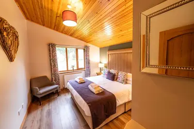 a bedroom with a bed and a chair in a room at Laurel Lodge 6 with Hot Tub in Newton Stewart
