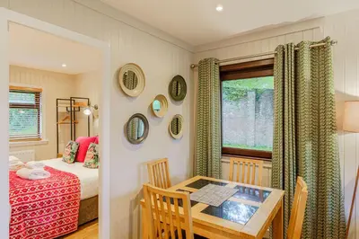 a room with a table and a bed and a window at Conifer Lodge 25 with Hot Tub in Newton Stewart