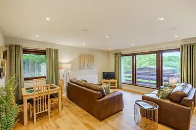 a living room with a couch and a table at Conifer Lodge 25 with Hot Tub in Newton Stewart