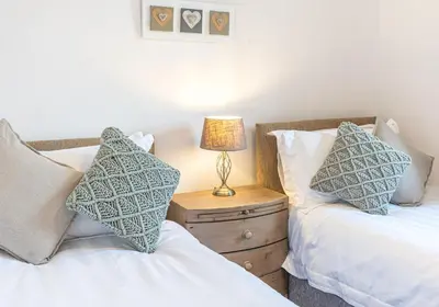 a bedroom with two beds and a lamp on a night stand at Lilac Cottage in Keswick