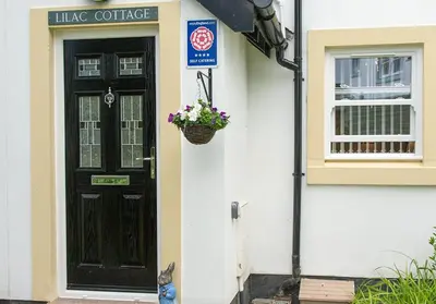 a black door with a basket of flowers on a house at Lilac Cottage in Keswick