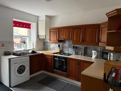 a kitchen with wooden cabinets and a washing machine at 17 Main Street in St Bees