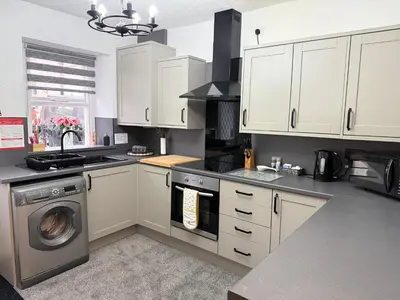 a kitchen with white cabinets and a washing machine at 18 Main Street in St Bees