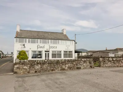 a building with a stone wall in front of it at Dershel Lodge in Dumfries