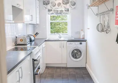 a white kitchen with a washer and dryer at 16 Greta Grove House in Keswick