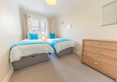 a bedroom with two twin beds and a dresser at 16 Greta Grove House in Keswick