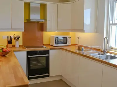 a kitchen with white cabinets and a microwave and a sink at 9 Greta Grove House in Keswick