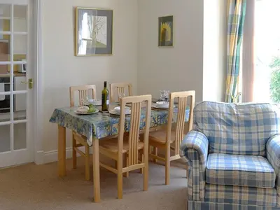 a dining room with a table and chairs with a bottle of wine at 9 Greta Grove House in Keswick