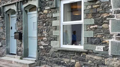 a stone building with a window with a person in it at Brandelhowe in Keswick