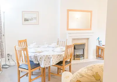 a dining room with a table and chairs and a fireplace at Latrigg View in Keswick