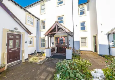 a white house with a brown door and a courtyard at Riverside View in Keswick