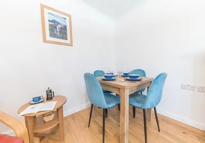a dining room with a wooden table and blue chairs at Riverside View in Keswick
