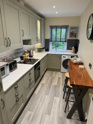 a kitchen with green cabinets and a wooden table at Skiddaw. 20 Greta Grove House in Keswick