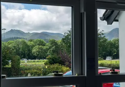 a window with a view of mountains and trees at Tiggs Place, 5 Howrahs Court in Keswick