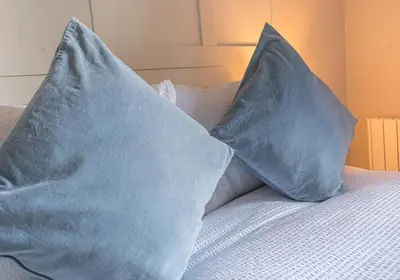 two blue pillows sitting on top of a bed at Victoria Apartment, Derwent House in Keswick